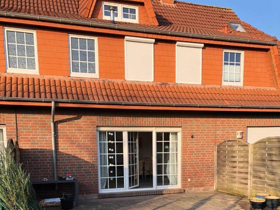 an orange brick house with an open garage at Ferienhaus Meeresleuchten, frisch renoviertes & gemütliches in Hooksiel