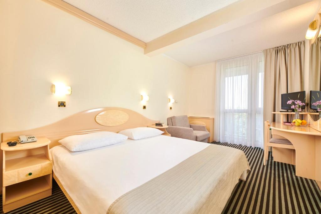 a hotel room with a bed and a desk at Hotel Istra Plava Laguna in Poreč