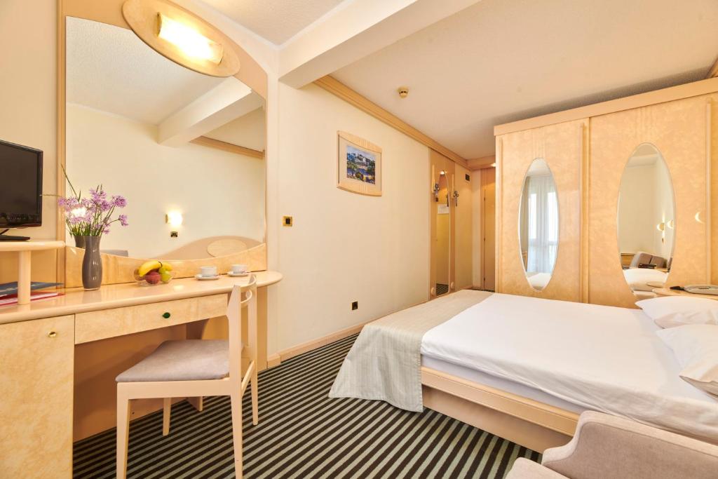 a hotel room with a bed and a desk at Hotel Istra Plava Laguna in Poreč