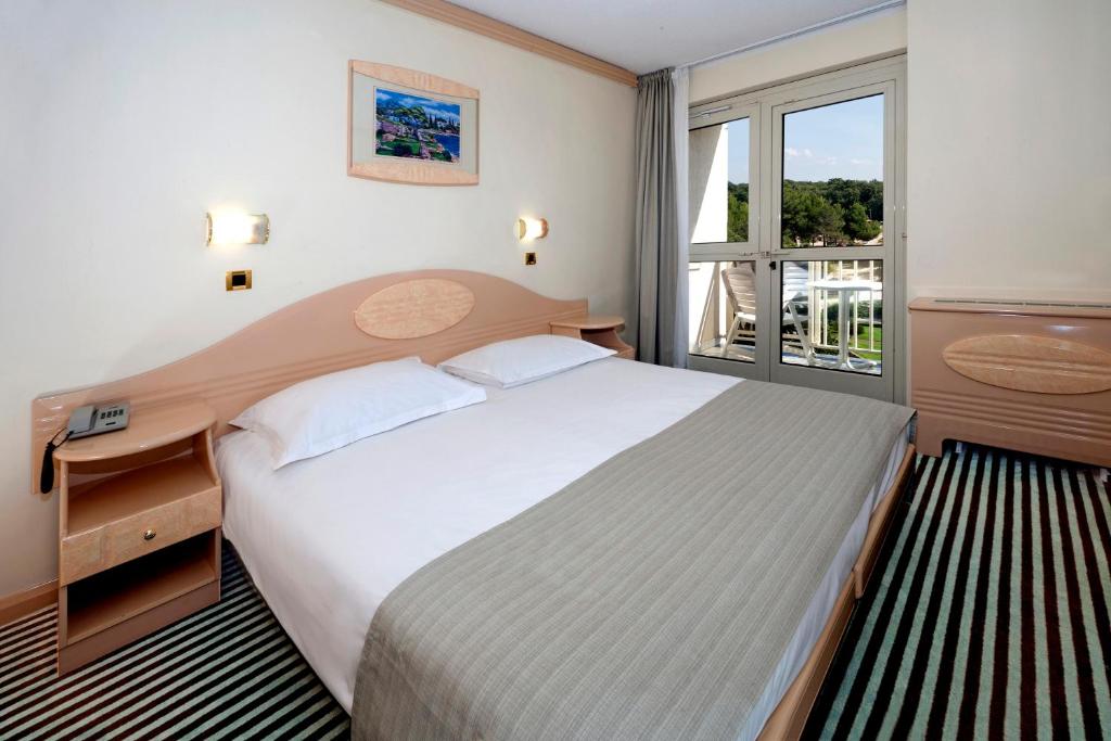 a bedroom with a large bed and a window at Hotel Istra Plava Laguna in Poreč