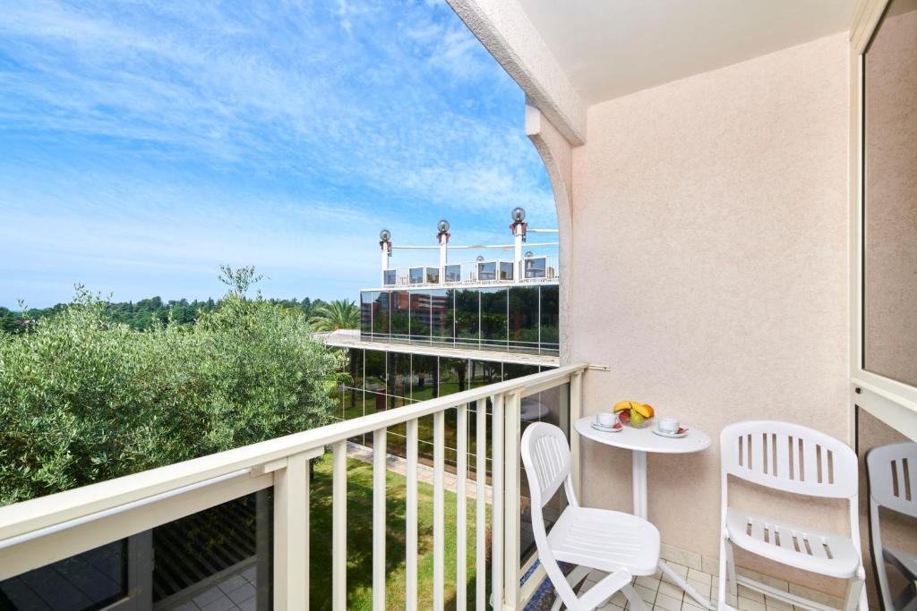 a balcony with two white chairs and a table at Hotel Istra Plava Laguna in Poreč