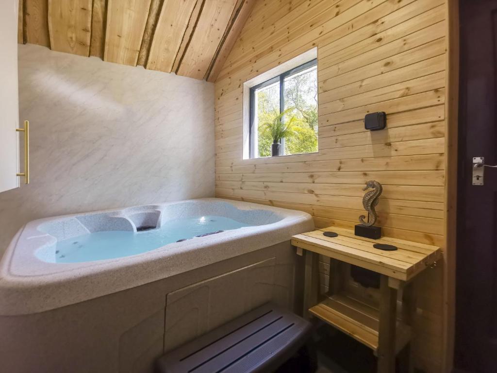 a large tub in a wooden bathroom with a window at Woodlands Family Retreat Windermere with Hot Tub and Sauna in Windermere