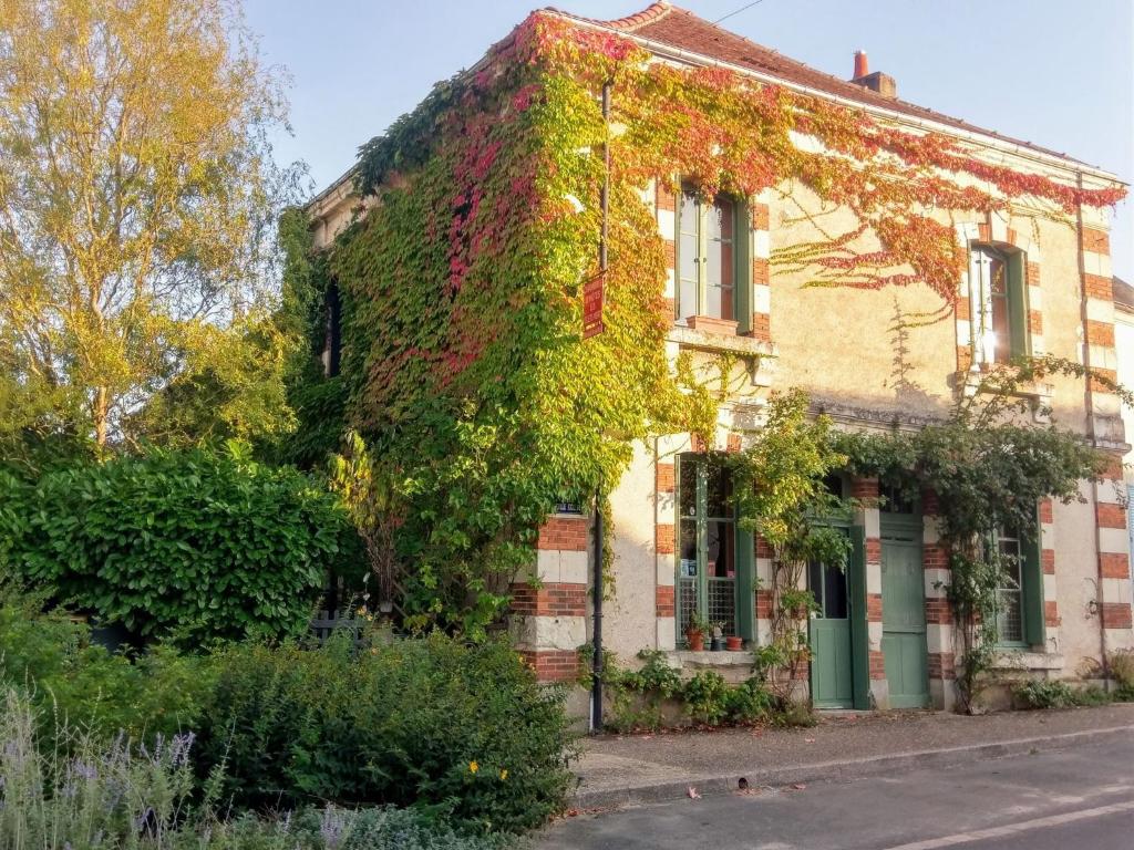 an old house with ivy growing on the side of it at Maison d'hôtes "les volets verts" et sa brocante in Écueillé