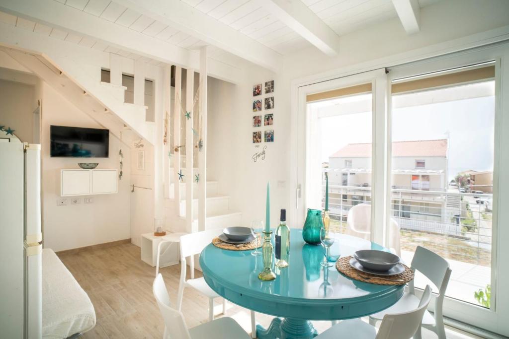 comedor con mesa azul y sillas blancas en MERMAID'S HOUSE, en Isola Rossa