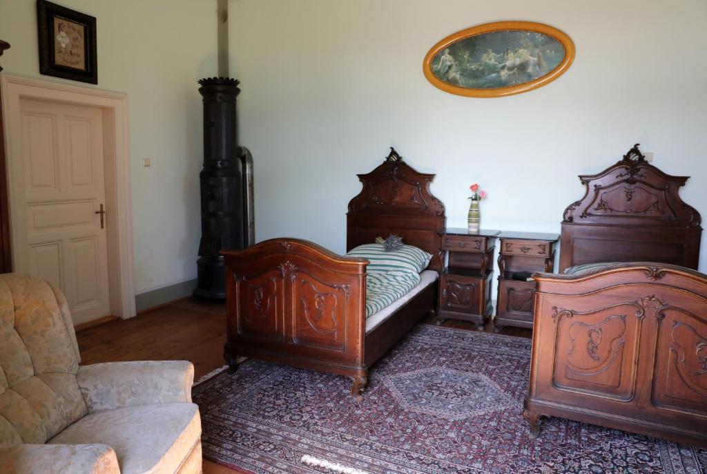 a bedroom with two large wooden beds and a couch at Zelenohorská pošta in Nepomuk