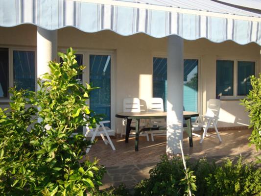 une terrasse avec une table et des chaises dans une maison dans l&#39;établissement Apartments Delfini, à Sveti Filip i Jakov
