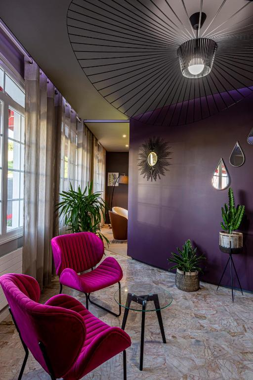 a lobby with pink chairs and a purple wall at Logis Hôtel Beau Site in Loubaresse