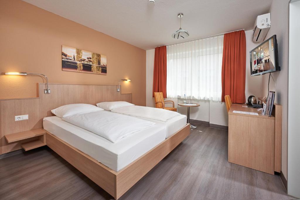 a bedroom with a large white bed and a desk at Hotel Touristik in Neuenburg am Rhein