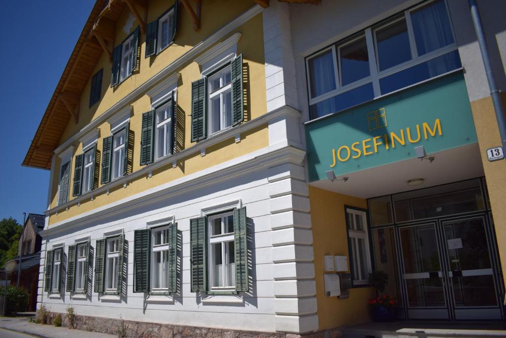 a yellow and white building with green shuttered windows at Frühstückspension Josefinum in Bad Aussee