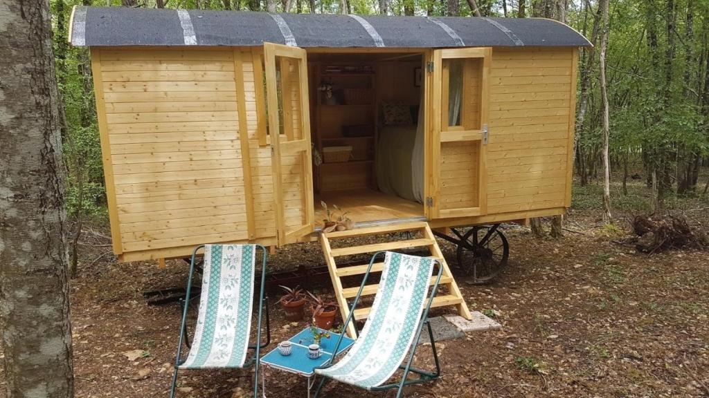 a wooden cabin with two chairs in front of it at Charming Cottage in Chauminet in Sougères-en-Puisaye