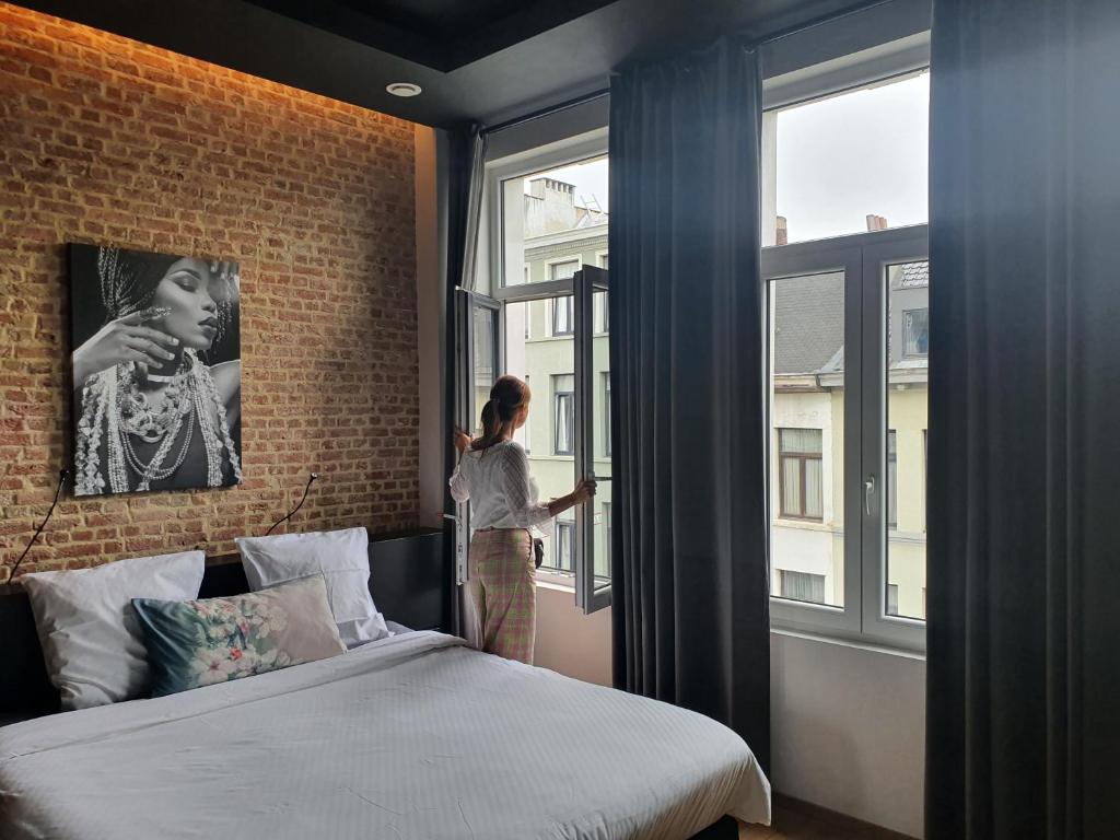 a woman looking out the window of a bedroom at Goodnight Antwerp in Antwerp