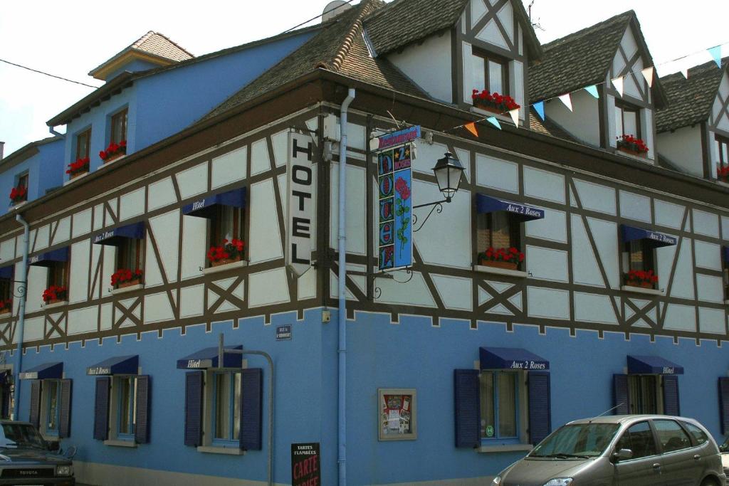 un edificio azul y blanco con un coche aparcado delante en Hôtel Restaurant Aux Deux Roses, en Neuf-Brisach