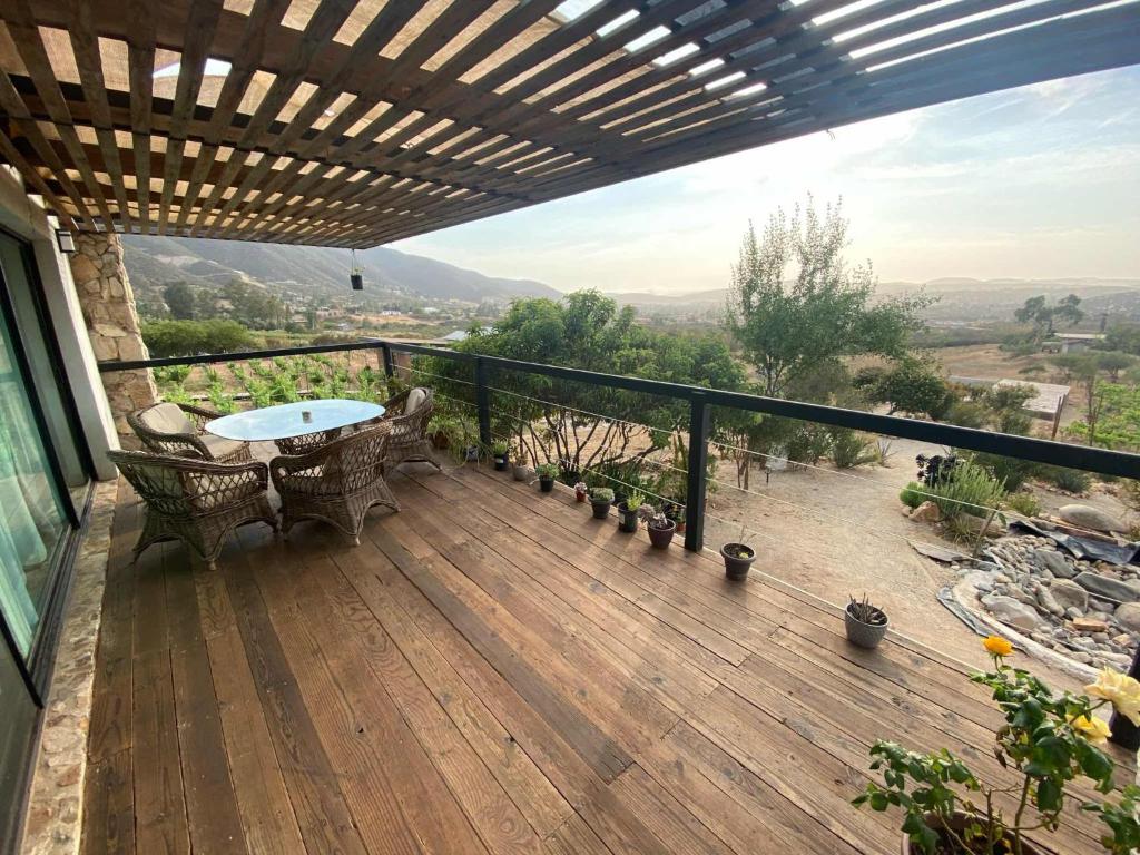 um deque de madeira com uma mesa e cadeiras numa varanda em Chalet Nativo - Fabulous Terrace & Vineyard em Valle de Guadalupe