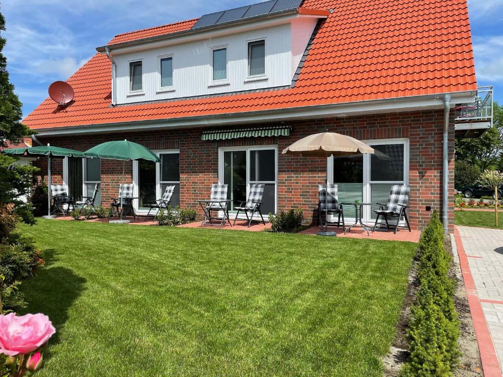 a house with a yard with chairs and umbrellas at Haus Nordseekrabbe in Greetsiel