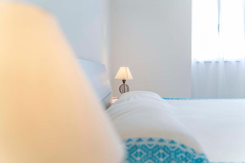 una camera con letto, lampada e finestra di Onda Blu ad Alghero