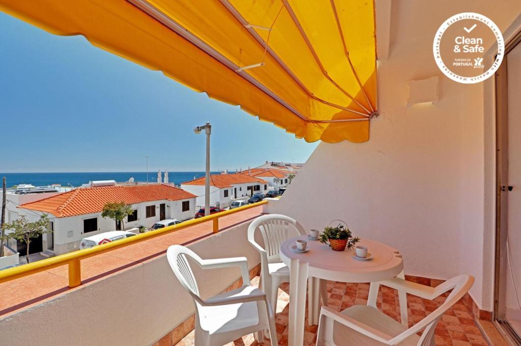 - un balcon avec une table, des chaises et un parasol dans l'établissement Albufeira Ocean View by Homing, à Albufeira