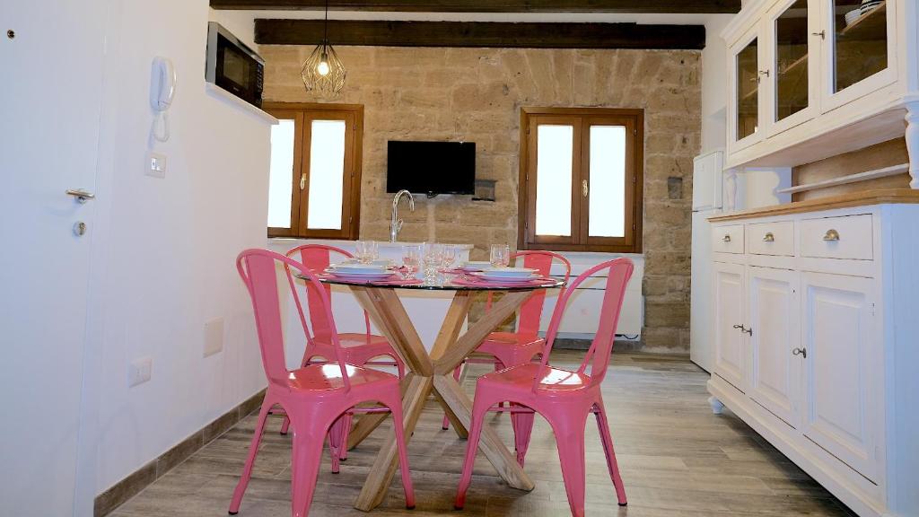 a dining room with pink chairs and a table at Welcomely - Santa Chiara in Alghero