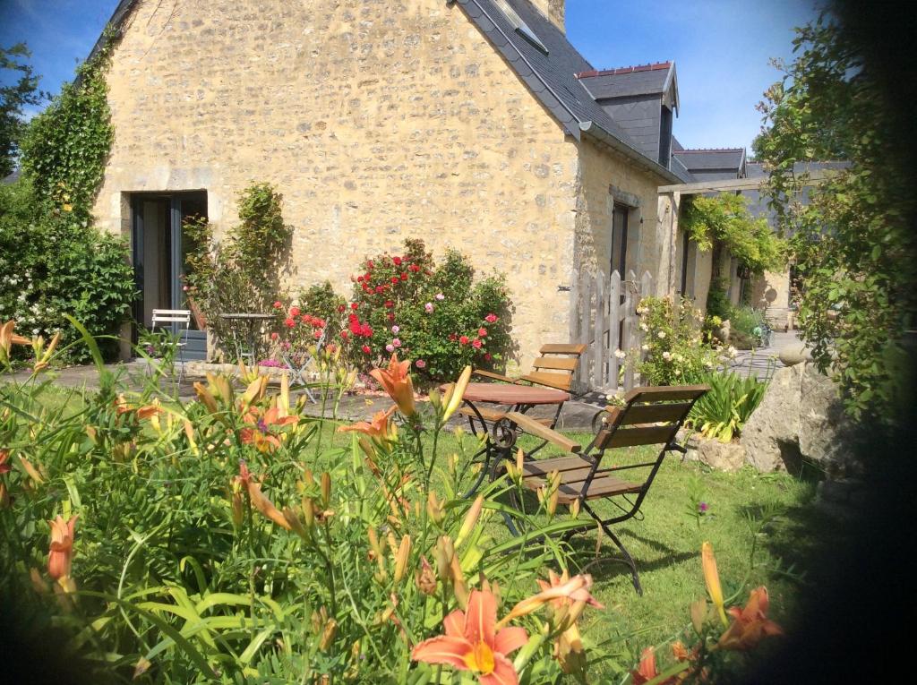 un giardino con due sedie e un tavolo e fiori di Chambres d'hôtes de charme ad Audouville-la-Hubert