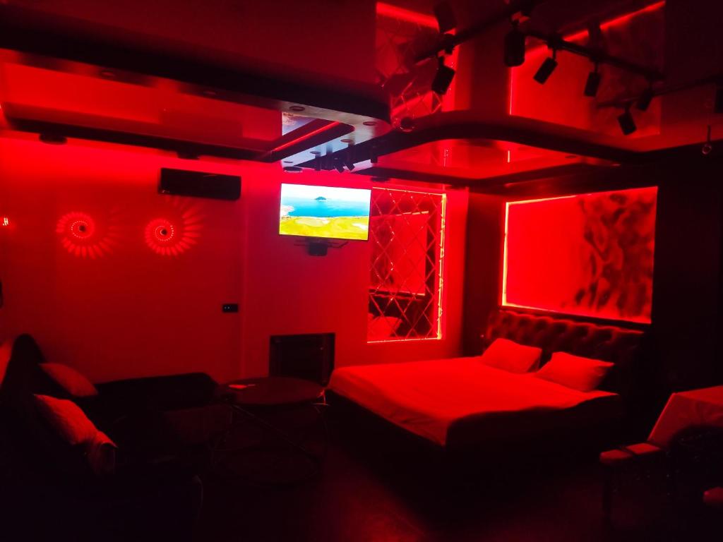 Cette chambre rouge comprend un lit et une télévision. dans l'établissement "DREAM ROOM" Тематические апартаменты Харьков! Цоколь!, à Kharkov