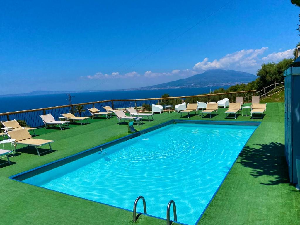 una piscina con sillas y el océano en el fondo en Corte Degli Ulivi Resort, en Vico Equense