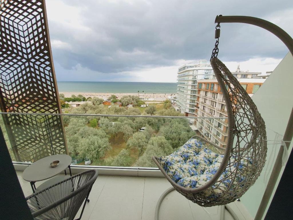 una silla mecedora en un balcón con vistas al océano en Mamaia Nord Bel Air, en Mamaia