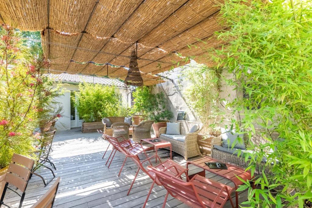 a patio with chairs and tables and a wooden roof at Hôtel Central in Avignon