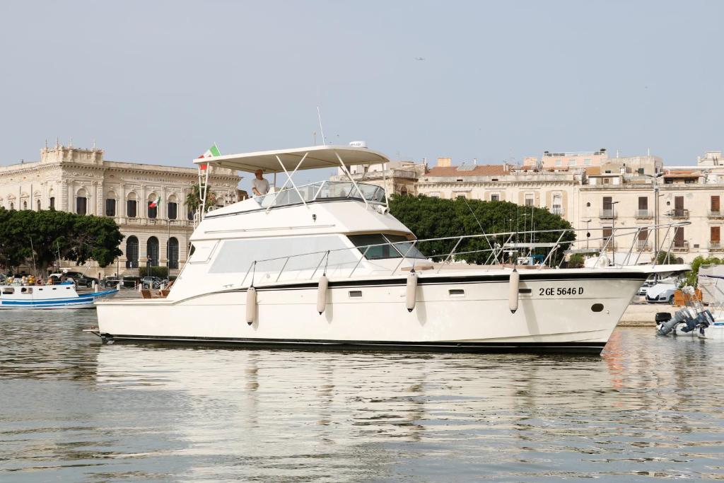 ein weißes Boot im Wasser vor einer Stadt in der Unterkunft Sàmos Bed & Boat in Marzamemi