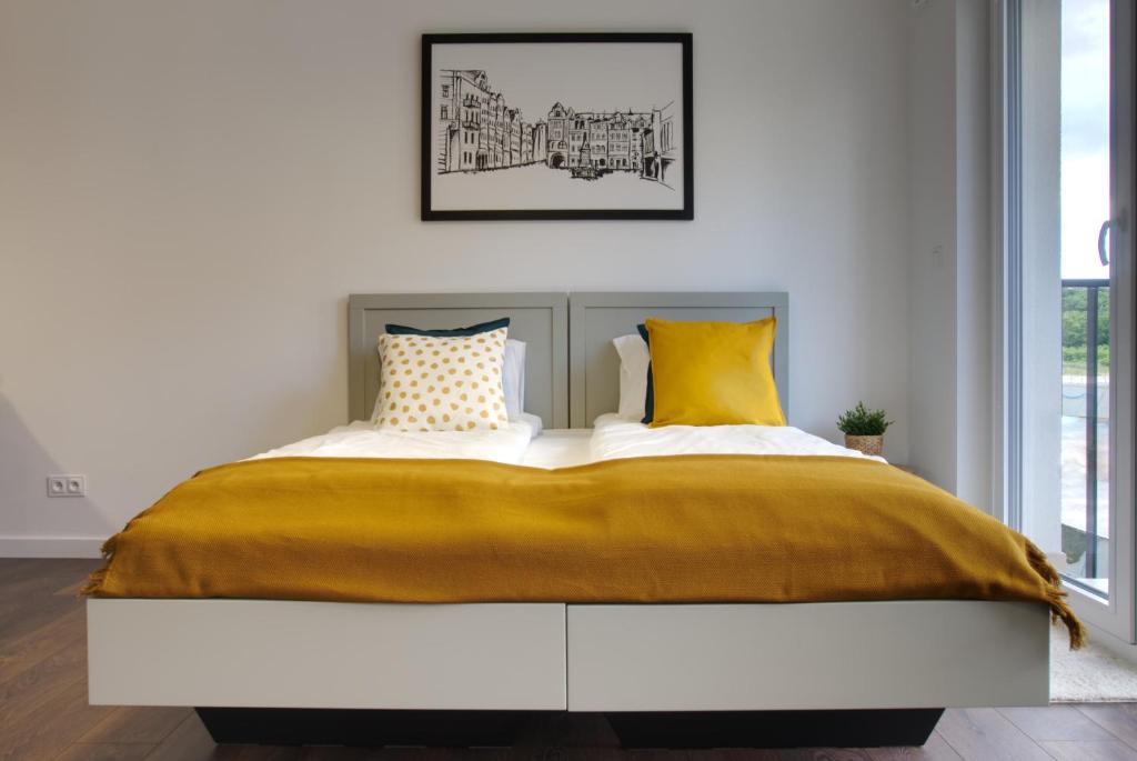a bedroom with a large bed with yellow pillows at Essence Apartments Topaz in Poznań