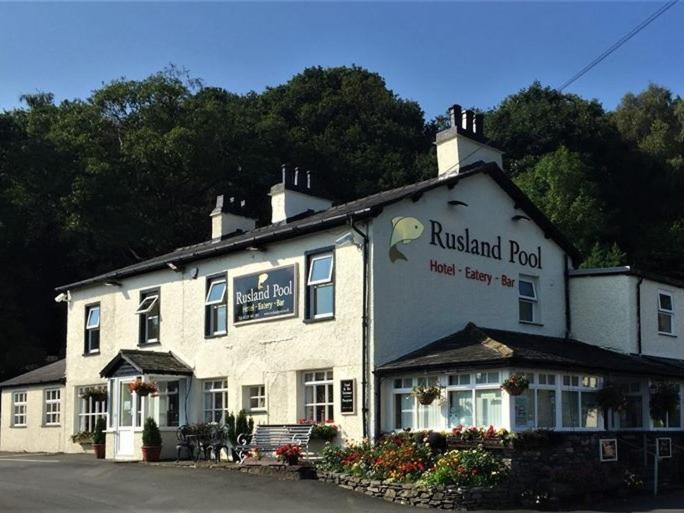 a white building with a restaurant on top of it at Rusland Pool Hotel in Bouth