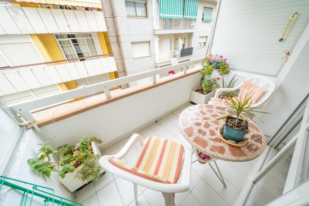 ピネダ・デ・マールにあるHomeHolidaysRentals Tarongersのアパートメントバルコニー(テーブル、椅子、植物付)