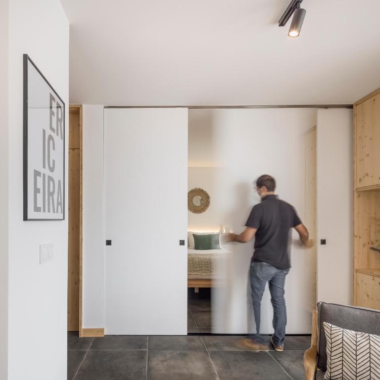 a man standing in a living room through a sliding door at Ericeira Prime Villas in Ericeira