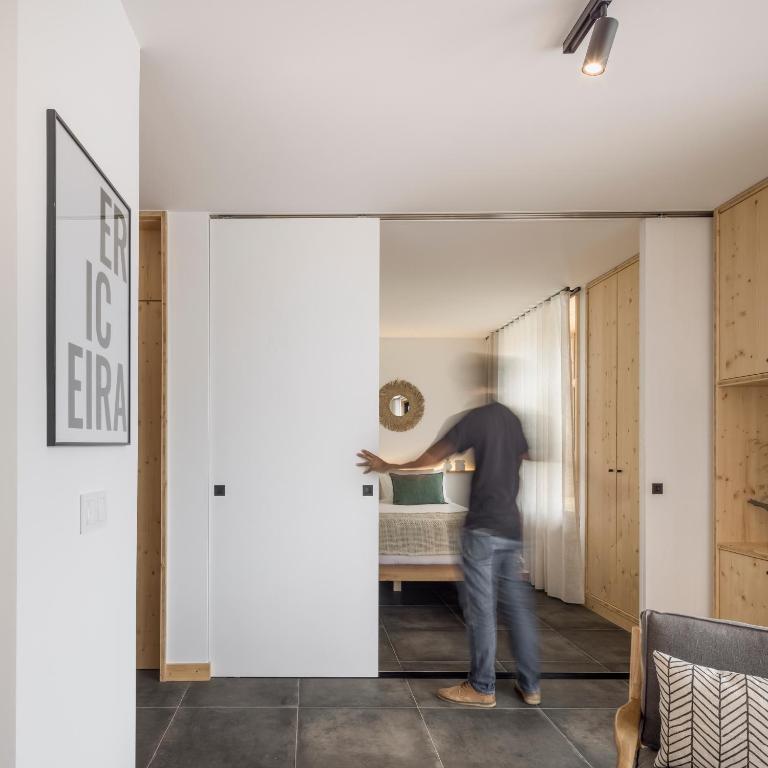 a man standing in a living room through a sliding door at Ericeira Prime Villas in Ericeira