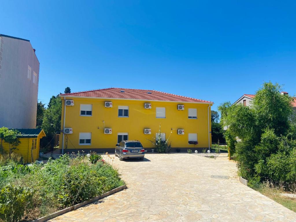 une maison jaune avec une voiture garée devant elle dans l'établissement Spacious apartment close to the sea in Kastel Luksic, à Kaštela