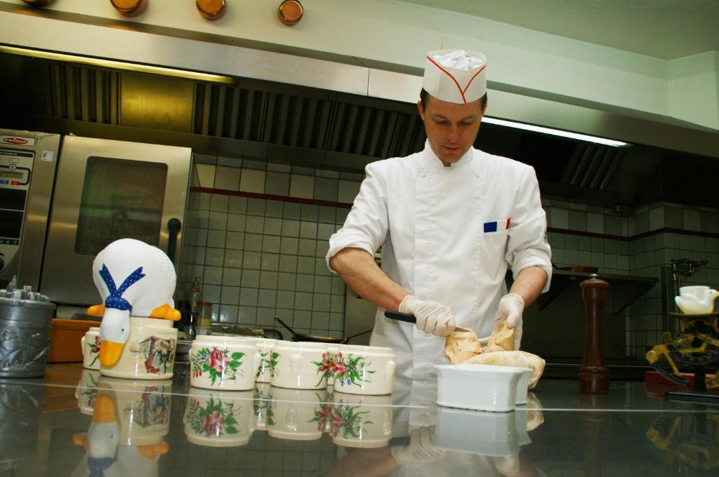 a chef is preparing food in a kitchen at Hôtel aux Bruyères in Orbey