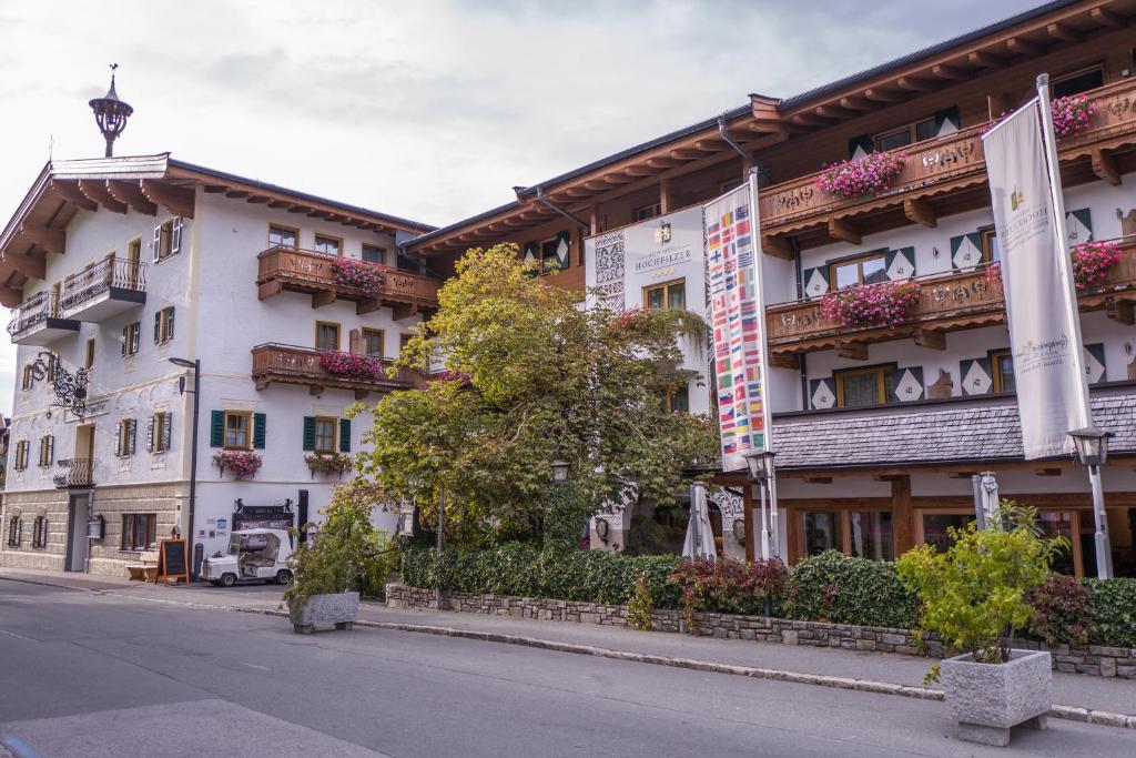 ein großes weißes Gebäude mit Balkon auf einer Straße in der Unterkunft Hotel Hochfilzer in Ellmau