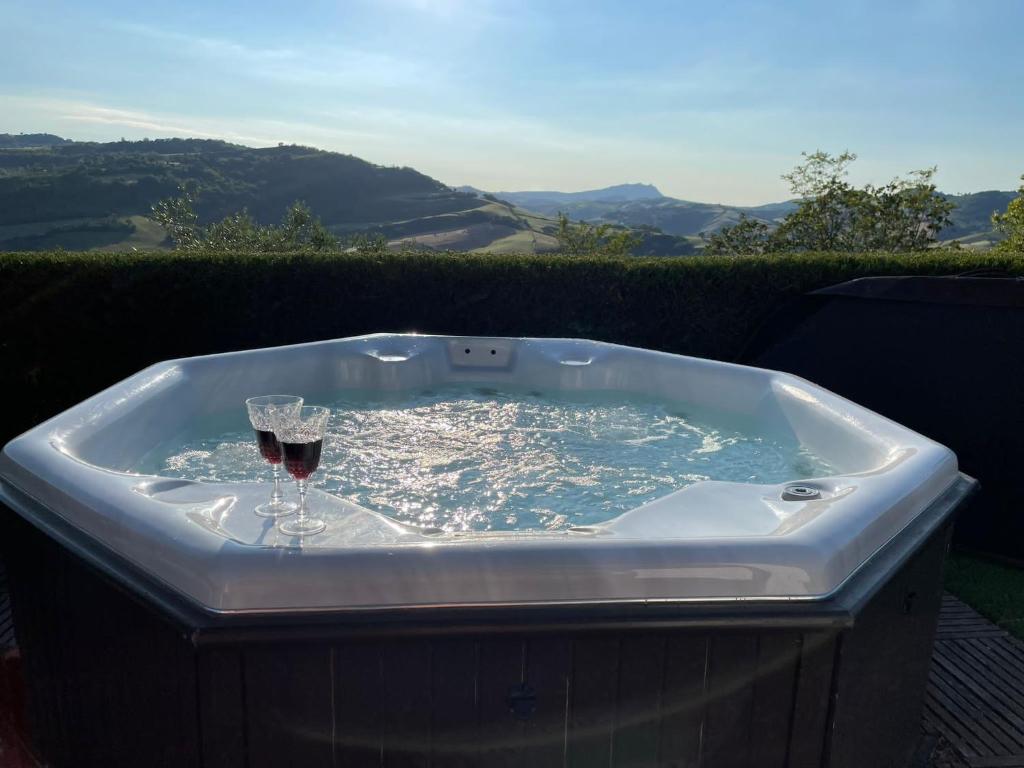 una vasca idromassaggio con un bicchiere di vino e un bicchiere di vino di Villa Tamara Country & Spa Suites a Montefiore Conca