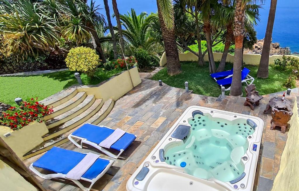 eine Terrasse mit Stühlen und einem Whirlpool am Meer in der Unterkunft CASA LOS POLVEROS in Fuencaliente de la Palma