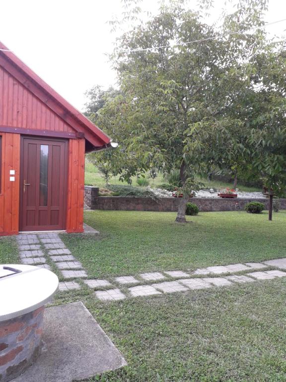 a yard with a red building and a tree at Mátyás Apartman in Tard