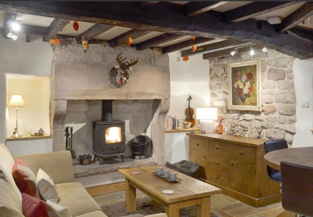 a living room with a stone fireplace and a table at Little Cottage in Cromford