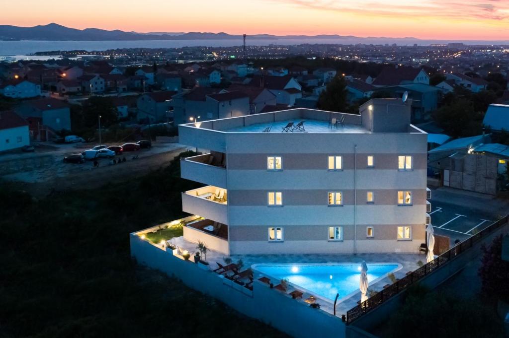 a building with a swimming pool at night at Oliva Vallis Apartments in Zadar
