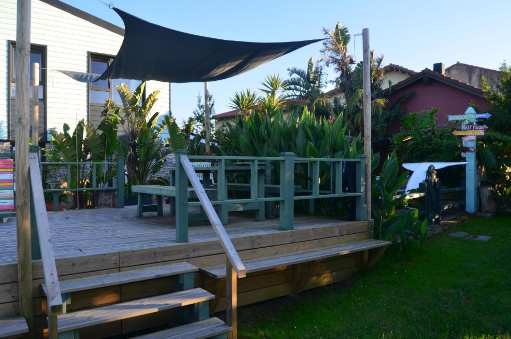 una terraza de madera con un banco y una sombrilla en Gangu Apartamentos Turisticos, en Suances