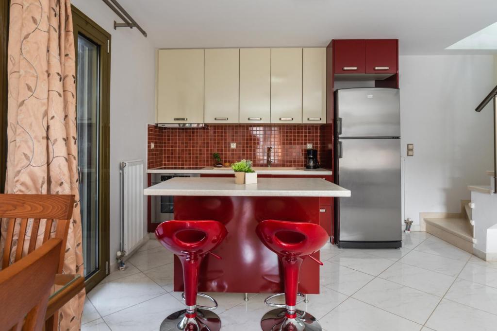 a kitchen with a red island with red stools at Maria's City Villa in Argostoli