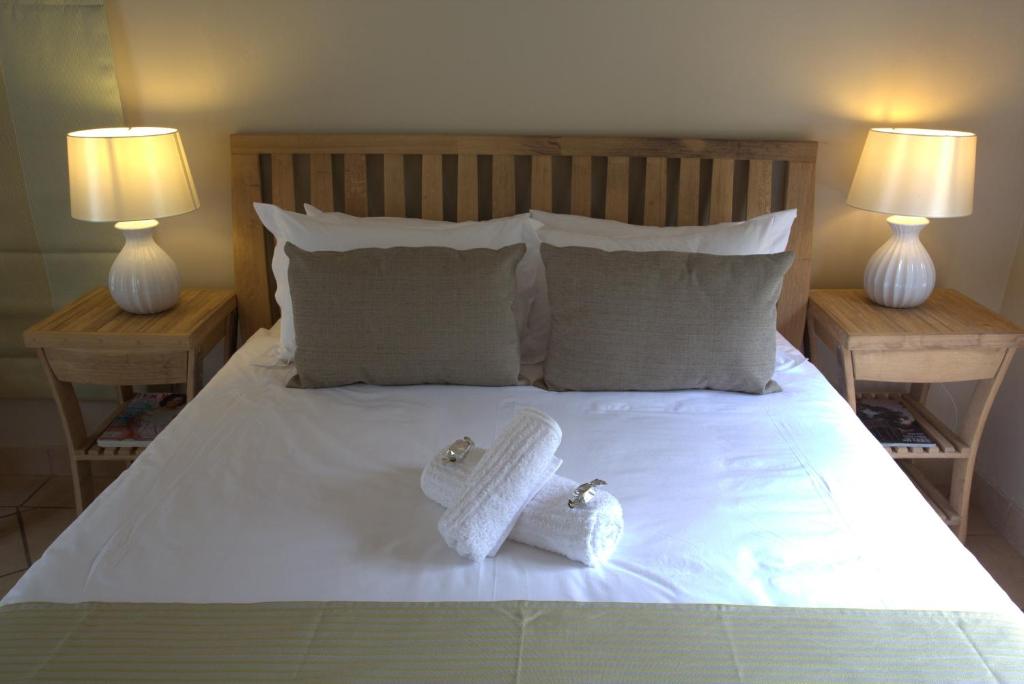 a bed with two towels on it with two lamps at Apple Cottages in George
