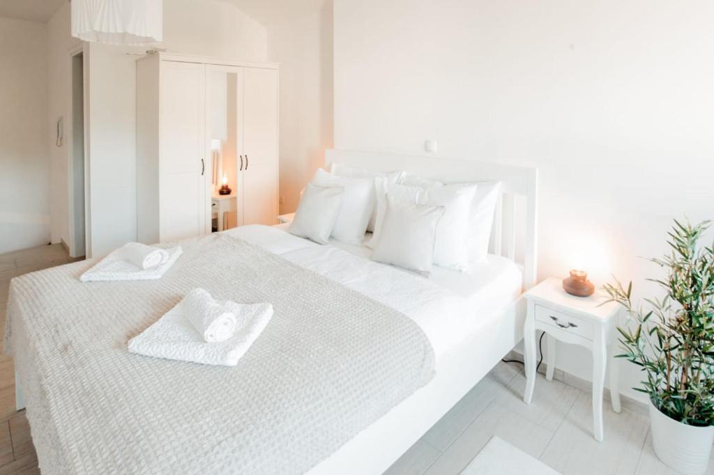 a white bedroom with a large white bed with white pillows at Kuća u centru in Pakoštane