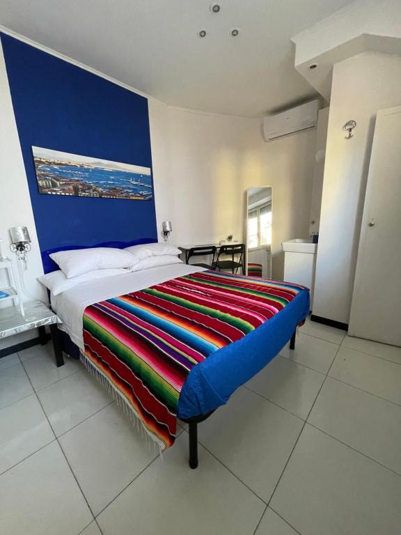 1 dormitorio con 1 cama grande y pared azul en DaRoDa Guest House Napoli, en Nápoles