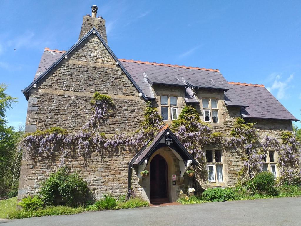 una vieja casa de piedra con flores púrpuras. en St David's Guesthouse, en Haverfordwest