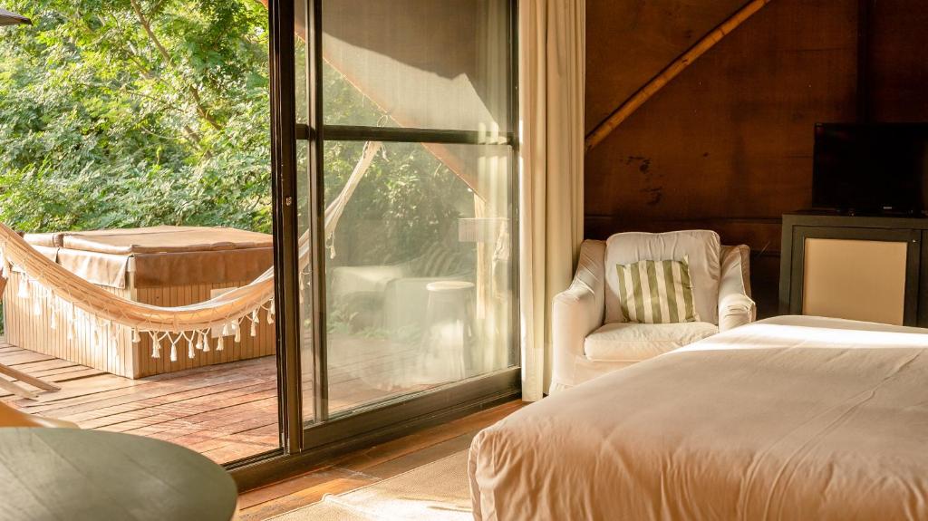 a bedroom with a bed and a chair and a balcony at Tava Lago in San Bernardino