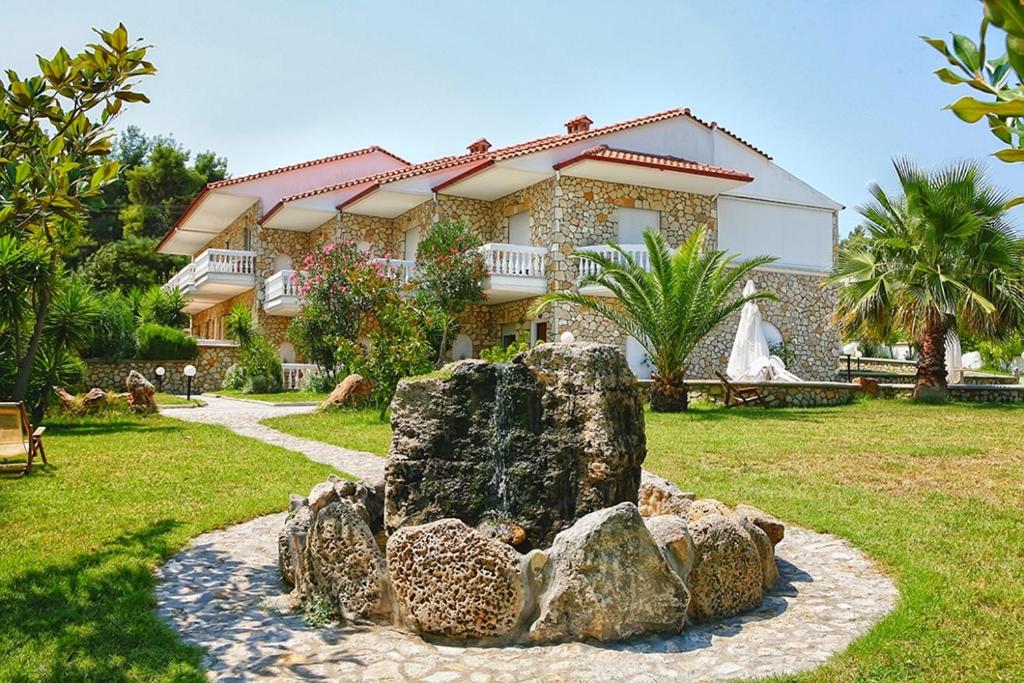 a house with a rock fountain in front of it at Chrouso Apartments in Paliouri