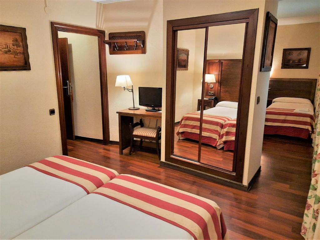 a hotel room with two beds and a mirror at Hotel Urogallo in Vielha