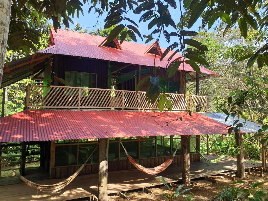a house with a red roof and hammocks in front at Reserva Natural Tucuchira in Santa Sofía